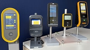 Fünf verschiedene Validatoren für den Ticketkauf stehen nebeneinander vor einer dunkelblauen Wand, mehrere Bildschirme zeigen Ticketauswahl und Preise