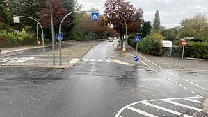 Blick auf eine nasse Straße mit Fußgängerüberweg und Verkehrsschildern an einer Kreuzung in Berlin.